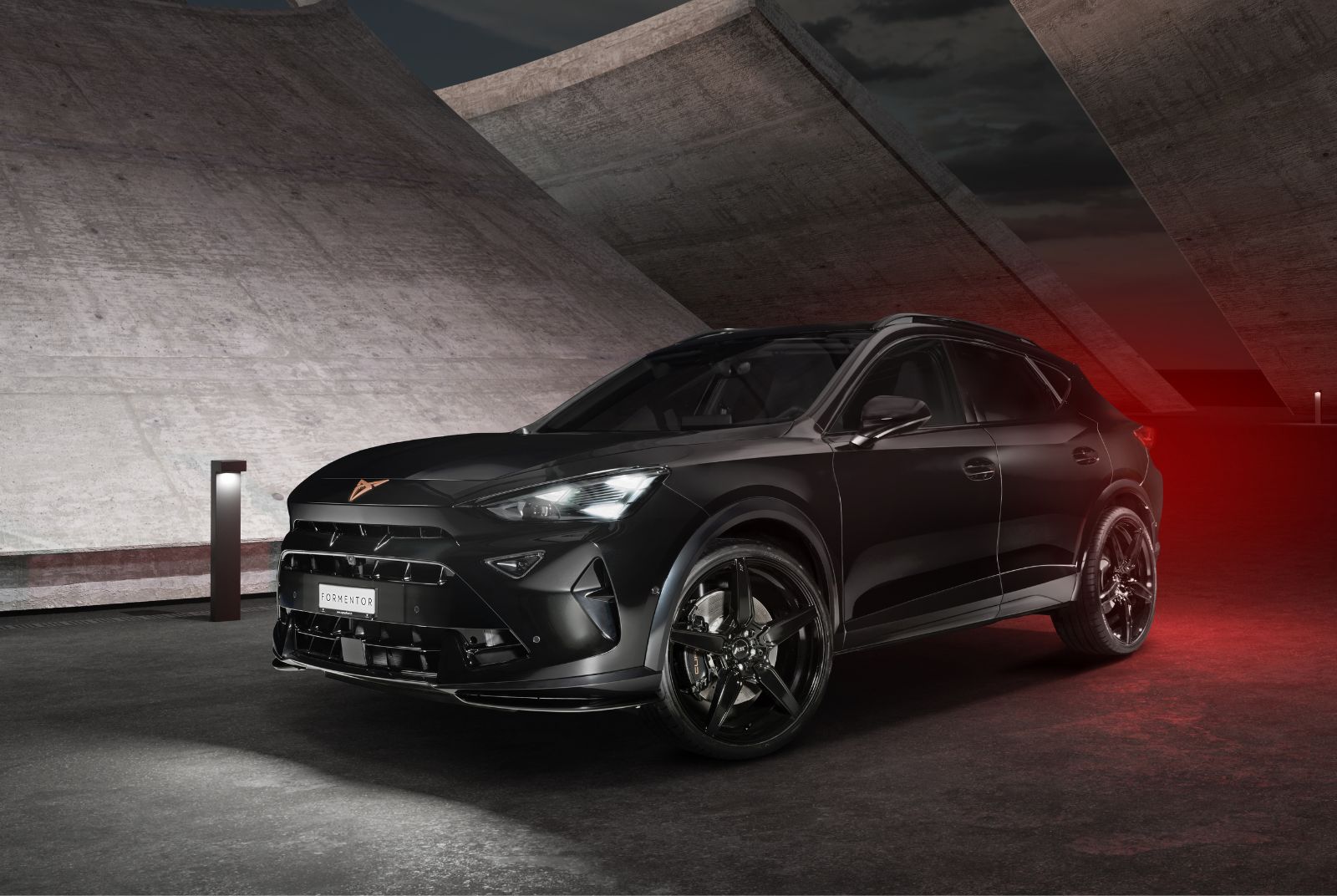 Seitenansicht des CUPRA Formentor, der in einer dunklen urbanen Umgebung geparkt ist, was die Designdetails der Black Edition betont.