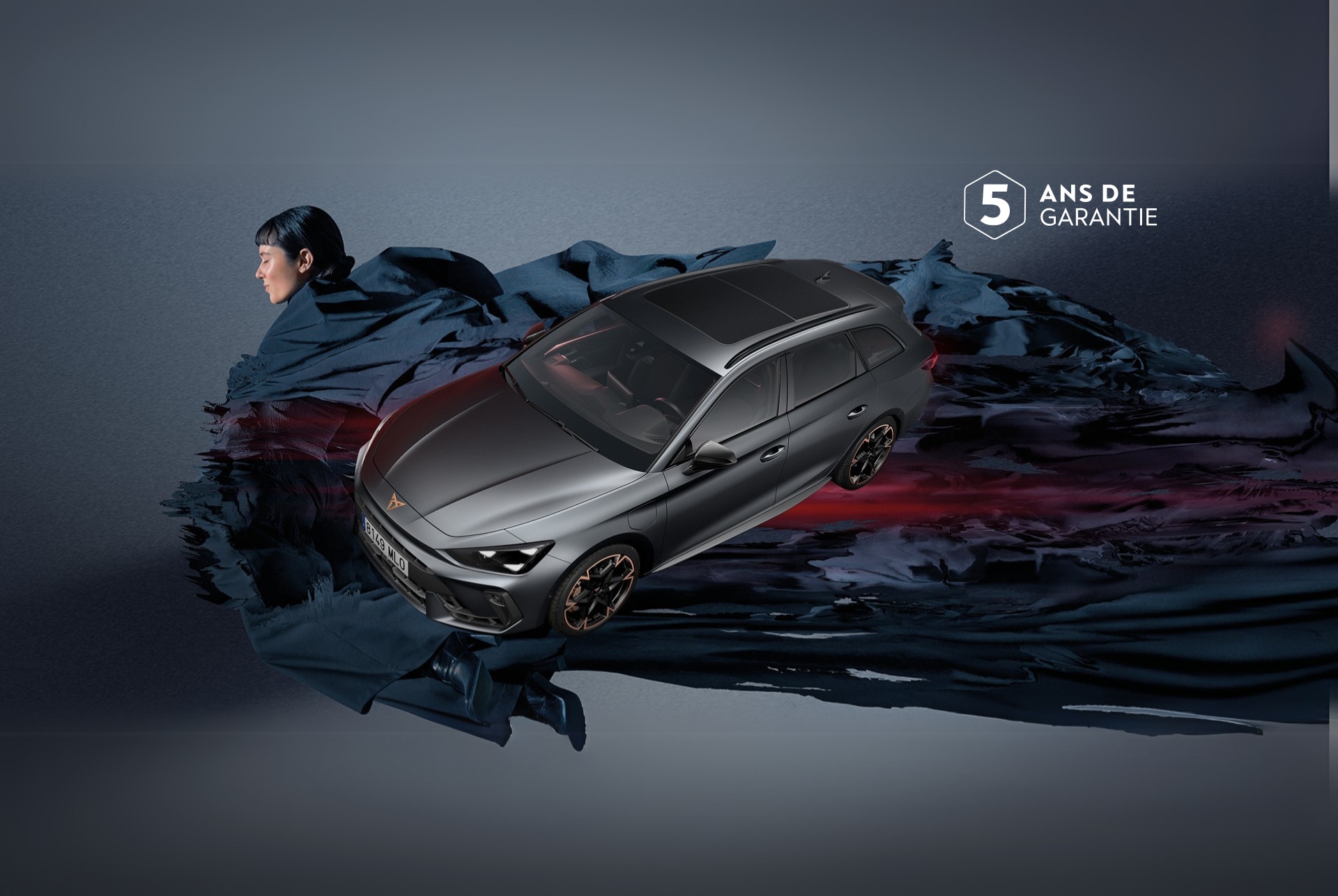 Vue grand angle de la nouvelle CUPRA Leon Sportstourer 2024 hybride sportive en Matte Grey, garée dans un environnement urbain devant de grandes fenêtres géométriques évoquant Gaudí.  