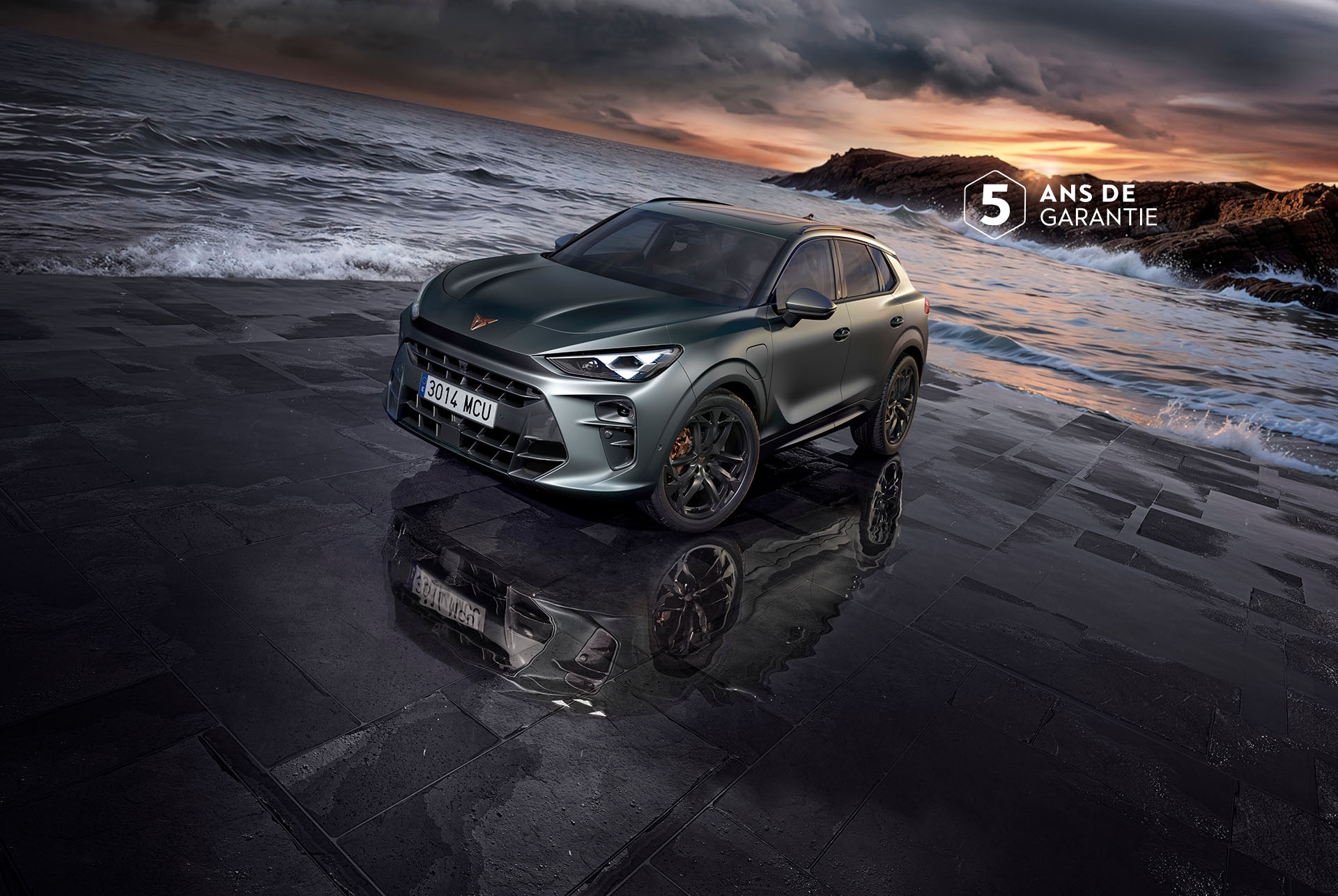 La nouvelle SUV CUPRA Terramar e-HYBRID sur un revêtement humide au bord de la mer, avec des phares élégants, des jantes en alliage léger modernes et un design avant évoquant un requin.