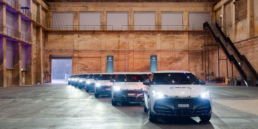 100 vollelektrische CUPRA Tavascan stehen in einer grossen Halle und sind mit einem Helion Schriftzug beklebt.