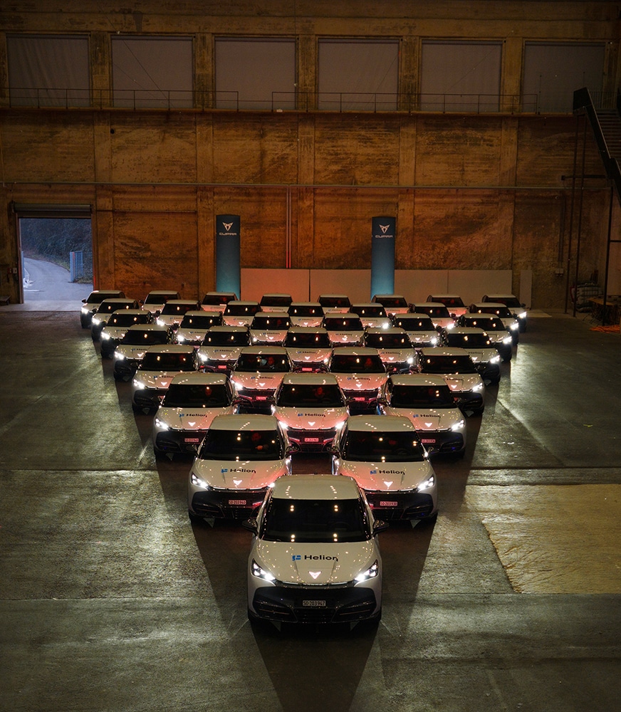 Ein CUPRA Besitzer und Benutzer eines Firmenwagens, der neben dem Geschäftswagen, dem Plug-in-Hybridfahrzeug CUPRA Leon steht und die my CUPRA App nutzt.