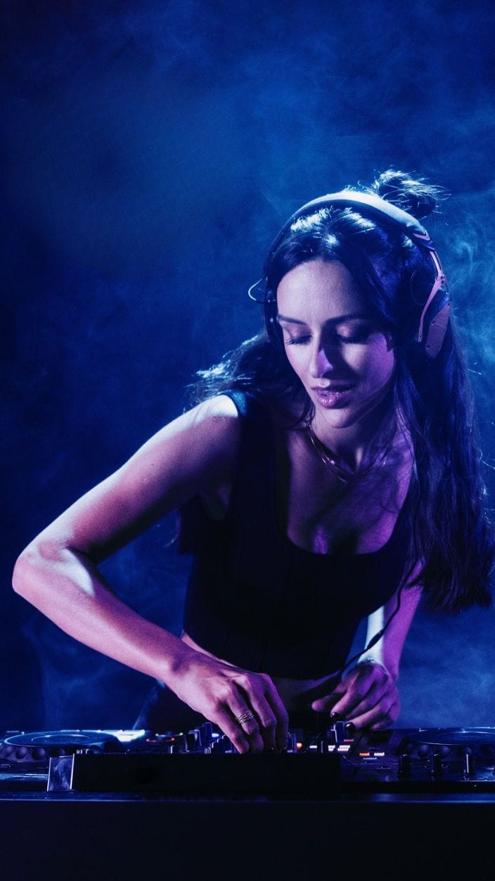 Eine junge Frau steht am DJ Pult