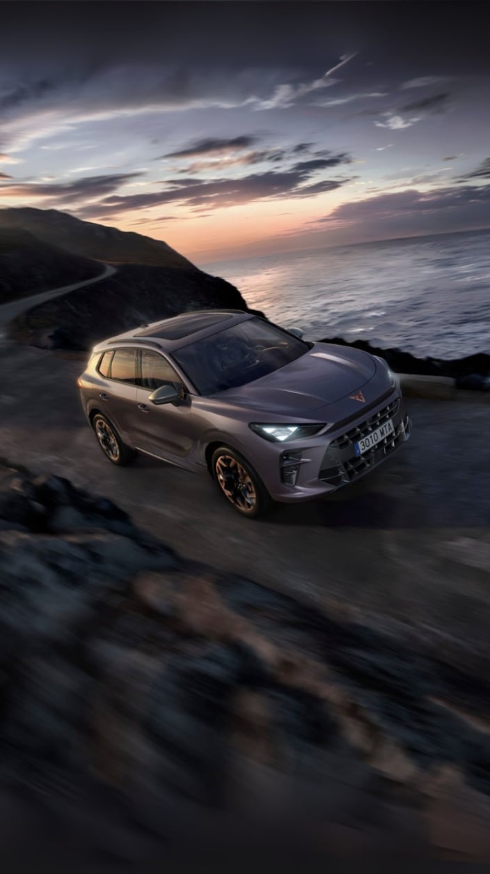 CUPRA Terramar fährt im Sonnenuntergang auf einer schmalen Strasse am Meer entlang