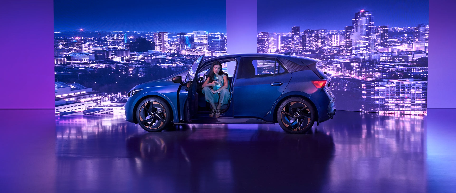 CUPRA Tavascan in Blue, in einer felsigen Umgebung parkiert, mit abgedunkelten Glasscheiben und Ambientebeleuchtung.