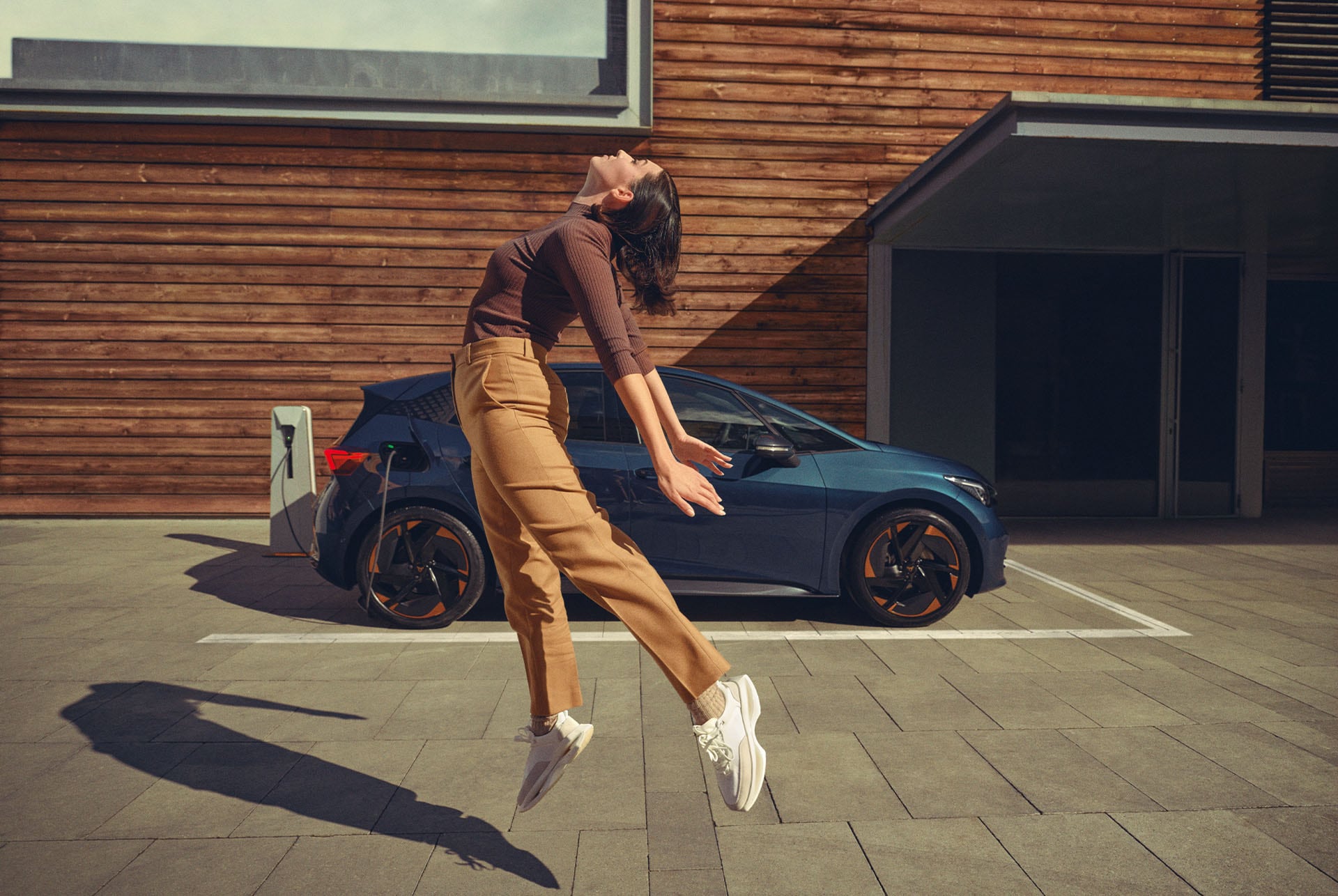 Une femme pose pendant la recharge d’une CUPRA Born de couleur Aurora Blue