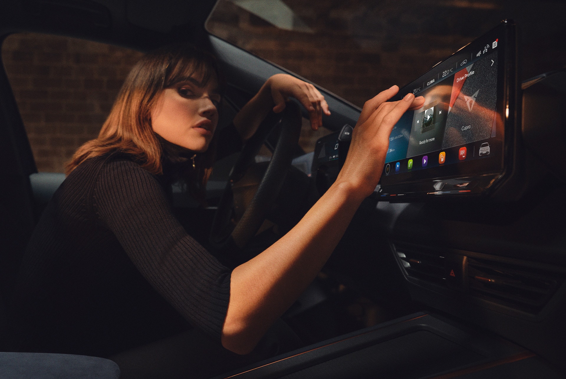 Femme à l’intérieur d’une CUPRA Born, utilisant le tableau de bord et l’écran d’info-divertissement