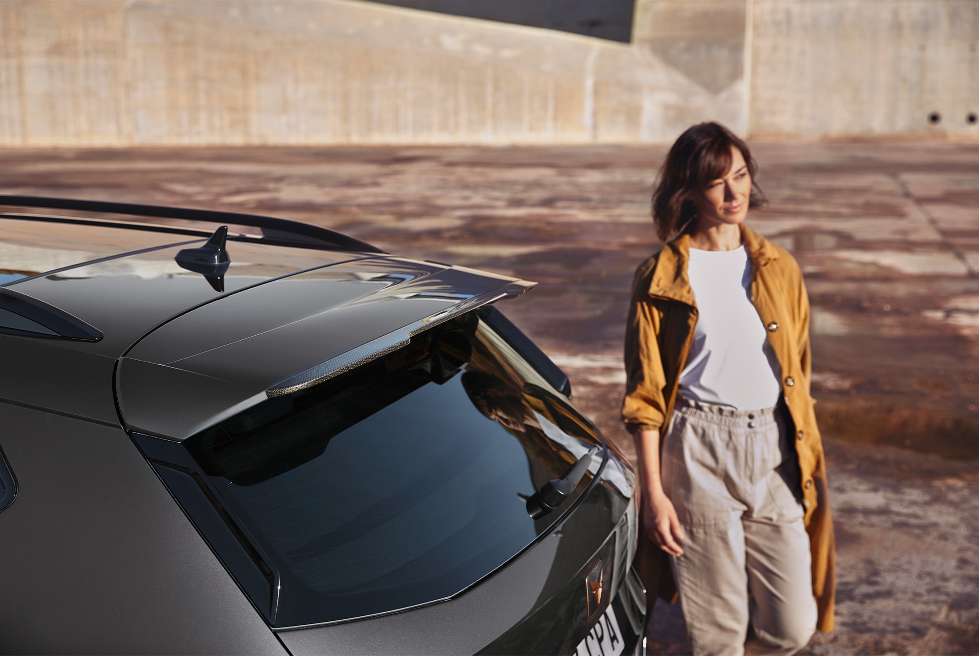 Vue arrière de la CUPRA Ateca avec une personne qui se tient à côté, soulignant les possibilités de paiement mensuel flexibles pour le service et l’entretien du véhicule.