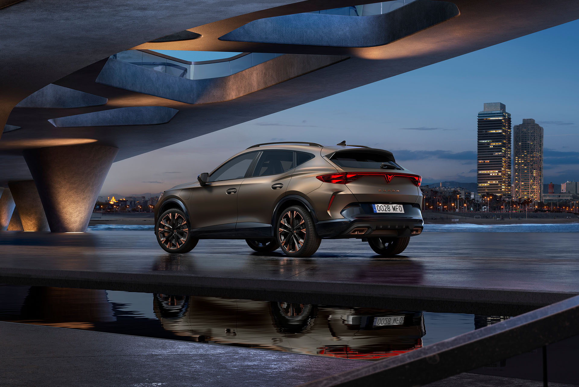 Perspective arrière de trois quarts de la nouvelle CUPRA Formentor hybride garée au bord de l'eau et de la ville. Le véhicule est incliné pour mettre en valeur son design arrière, ses feux et son double échappement sportif.