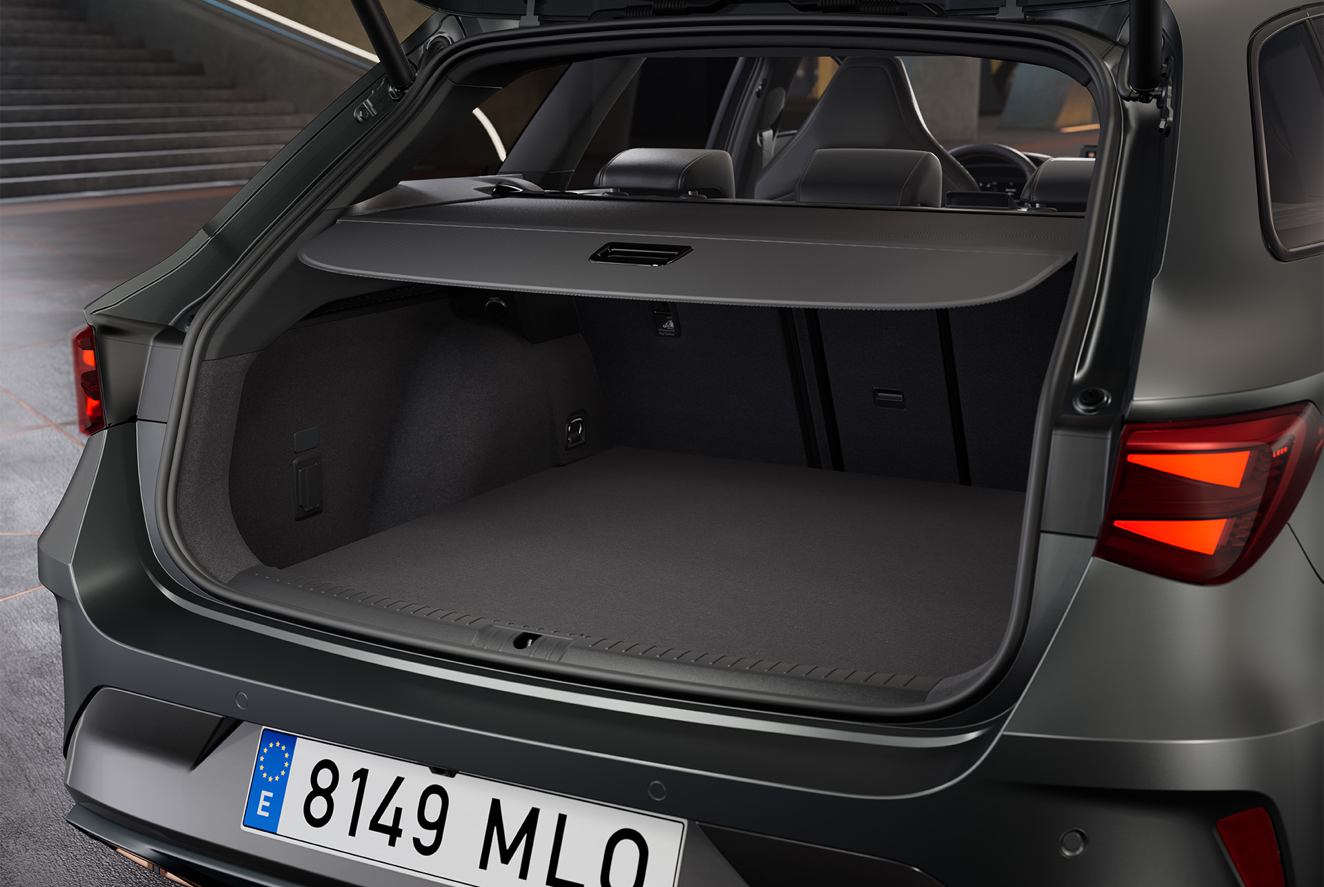 Coffre ouvert de la nouvelle CUPRA Leon Sportstourer hybride grise, surface de chargement spacieuse avec intérieur noir. Le coffre contient un sac.