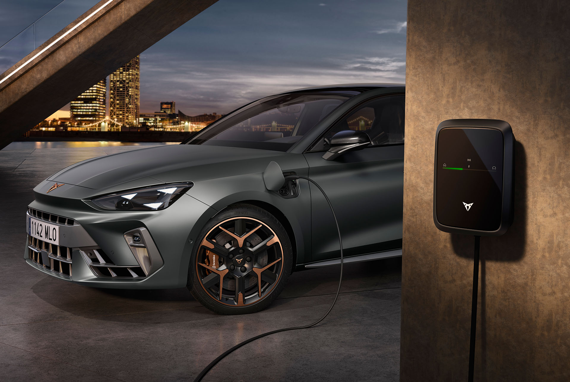 Vue de face de la nouvelle CUPRA Leon Sportstourer 2024 hybride en Enceladus Grey, en cours de recharge. Phares angulaires et jantes en alliage léger avec accents cuivrés.