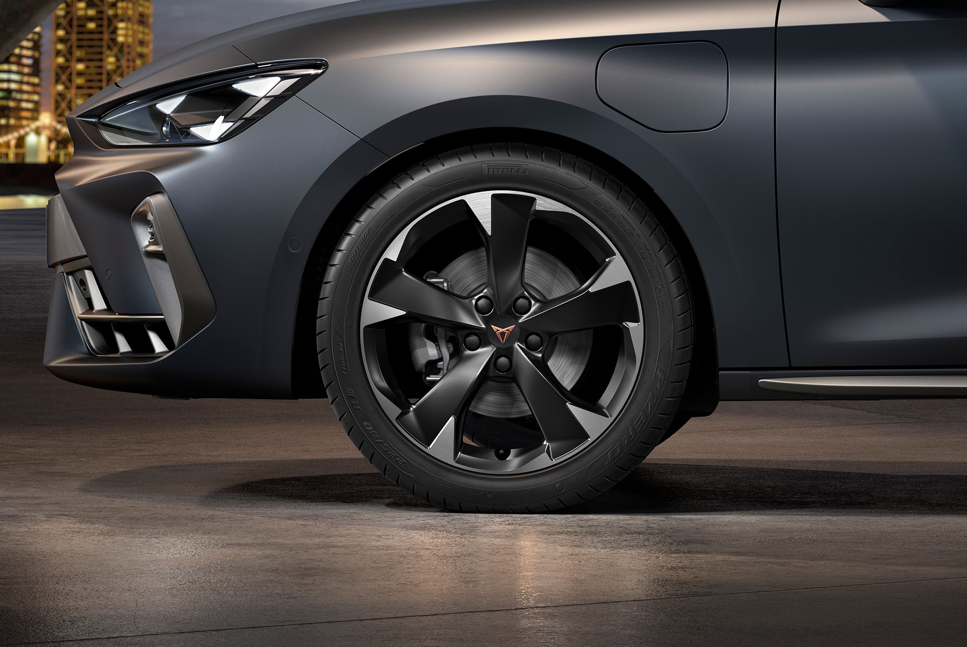 Frontansicht der gefrästen silbernen Garbi-Leichtmetallfelge links für den neuen CUPRA Leon 2024, Reifen, Signature-Scheinwerfer und Karosserie in Matte Grey