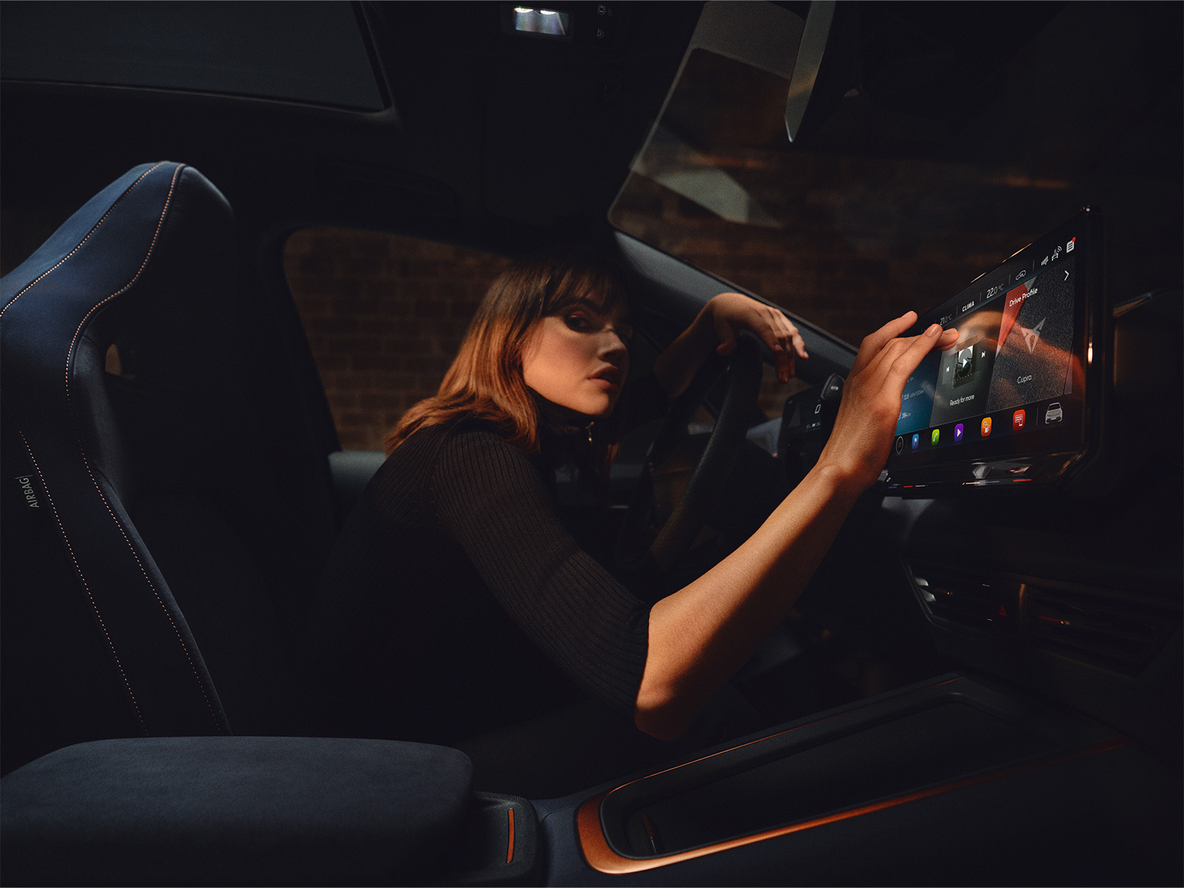 Eine Frau nutzt das Infotainment-Gerät im Fahrzeug, um nach Over-the-Air-Updates zu suchen und sicherzustellen, dass sie die neueste CUPRA Software hat.