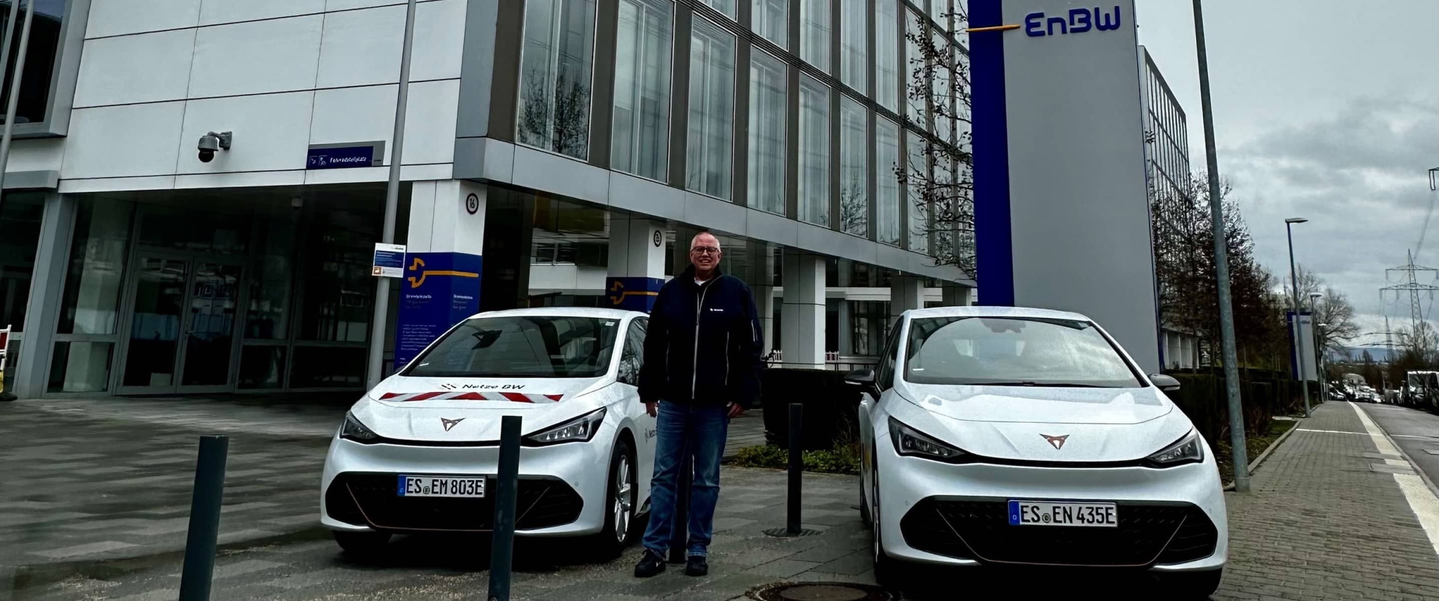 Zwei weisse CUPRA Born Flotten-Fahrzeuge vor dem EnBW Gebäude