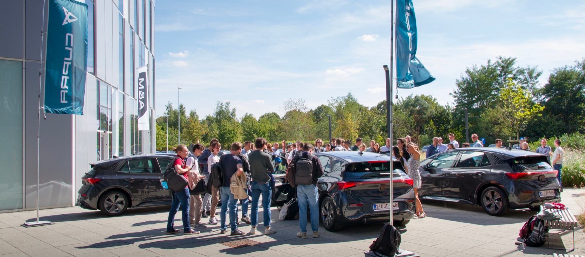 Elektrofahrzeuge, Firmenwagen vor den Cegeka-Büros, Bäume und blauer Himmel.