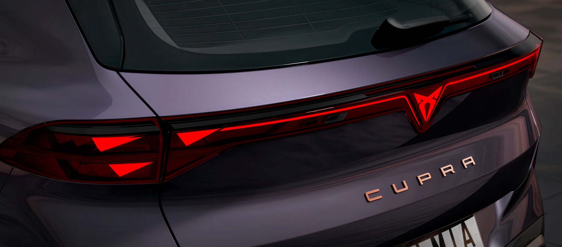 Nahaufnahme von cupra terramar Vz hinten in der Farbe, dunkle Leere, phev Rücklichter mit beleuchtetem cupra Logo und kupferfarbenem Akzentschriftzug.