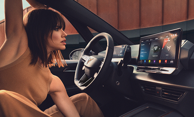 Una donna che visualizza gli aggiornamenti OTA CUPRA sul sistema di infotainment della sua auto.